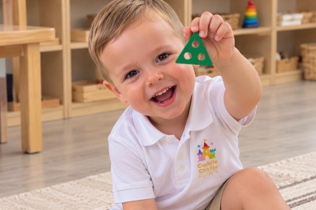 A smiling toddler holding up a green shape from a Montessori shape-sorting puzzle