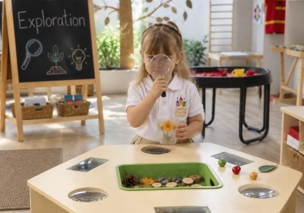 A girl looking through a magnifying glass at the discovery table in the Exploration Room